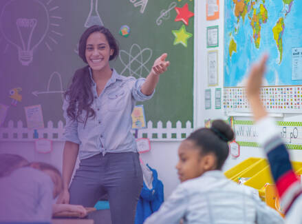 Teacher smiling and pointing at a student with hand raised